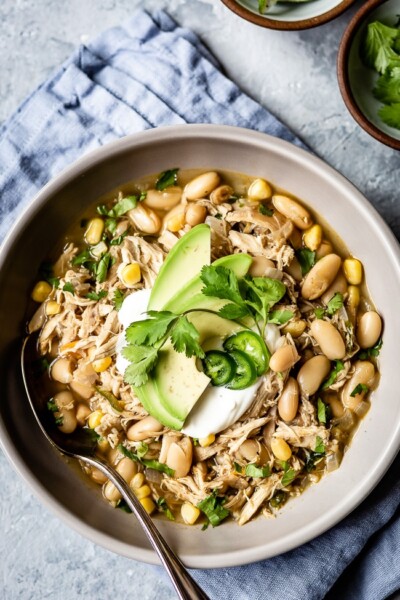 Healthy white chicken chili in a bowl and garnished with chili toppings like avocados and cilantro